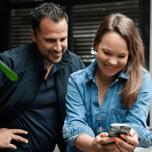 Man en vrouw kijken glimlachend samen naar een telefoon