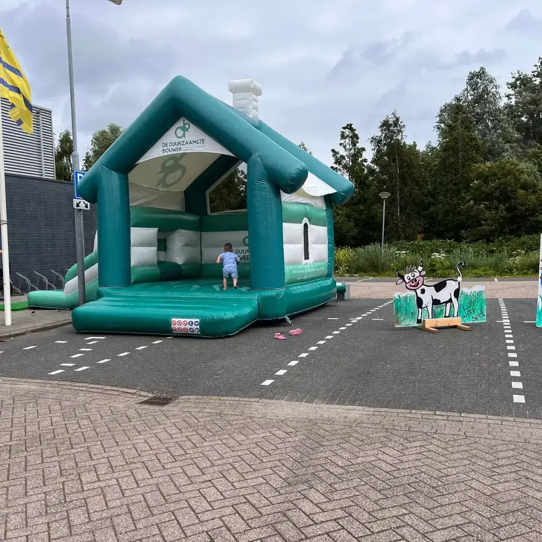 Kind speelt op groen-wit springkussen in de vorm van een huis van De Duurzaamste Bouwer