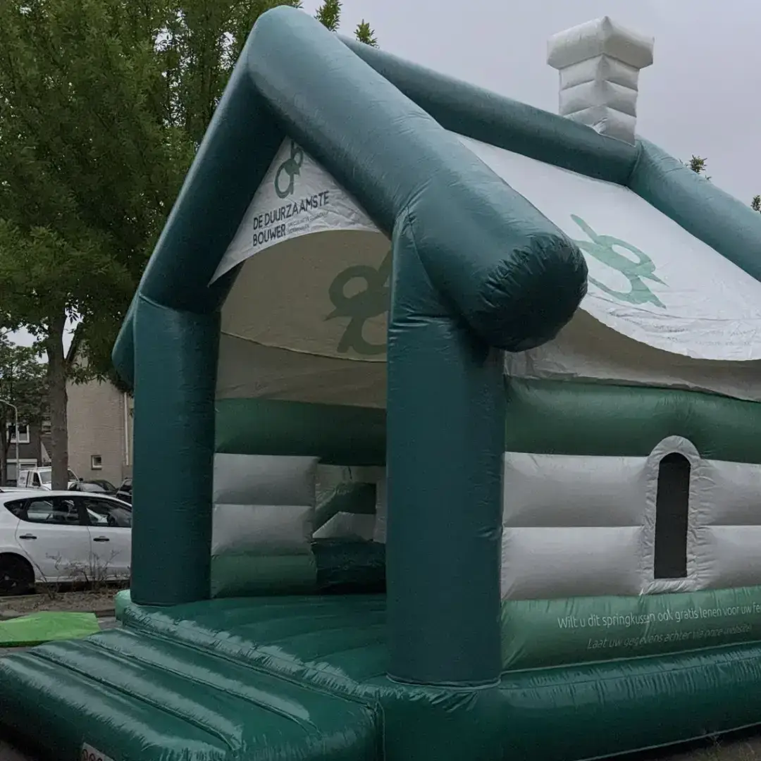 Groen-wit springkussen in de vorm van een huis met logo van De Duurzaamste Bouwer